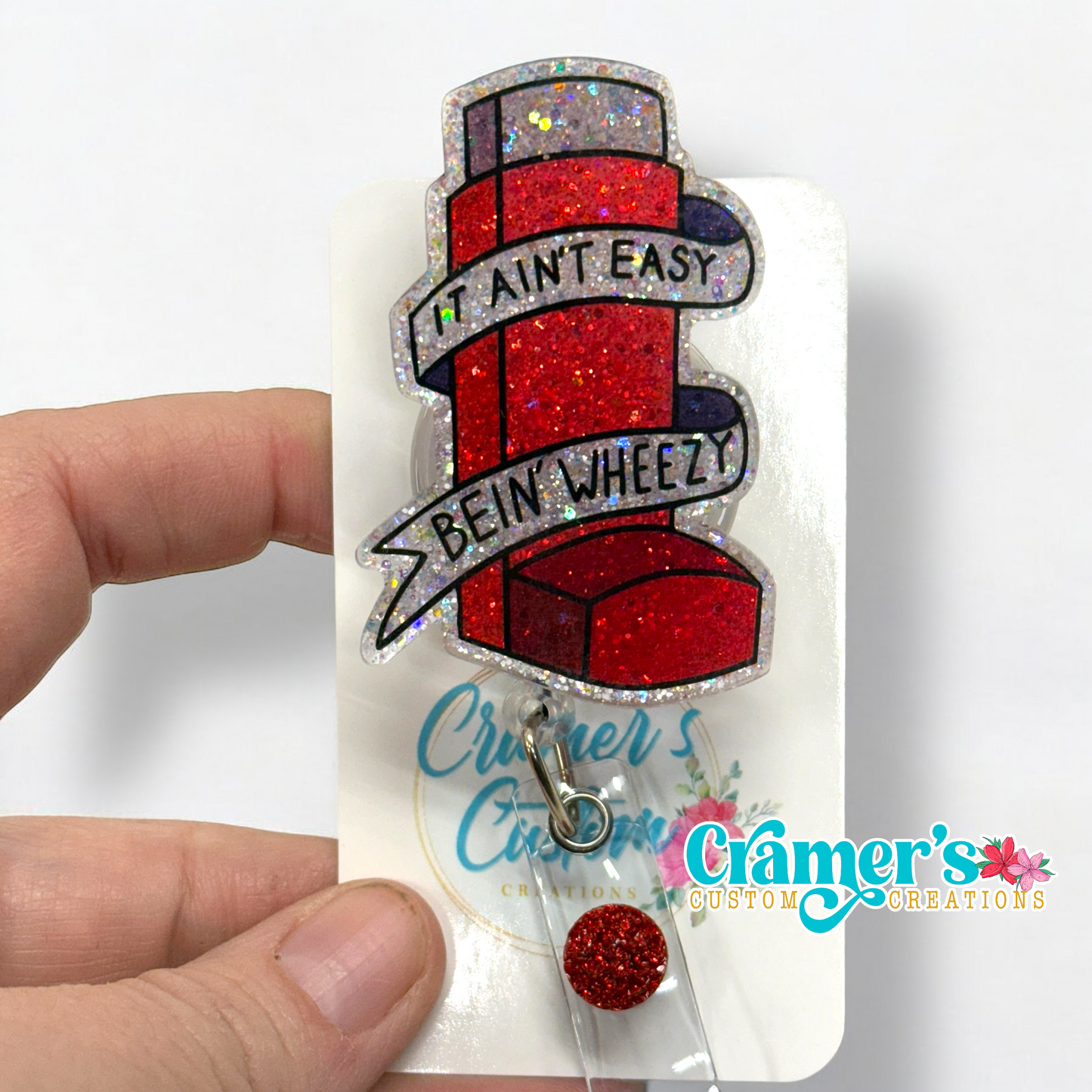 Red glitter inhaler badge reel that says it aint easy being wheezy