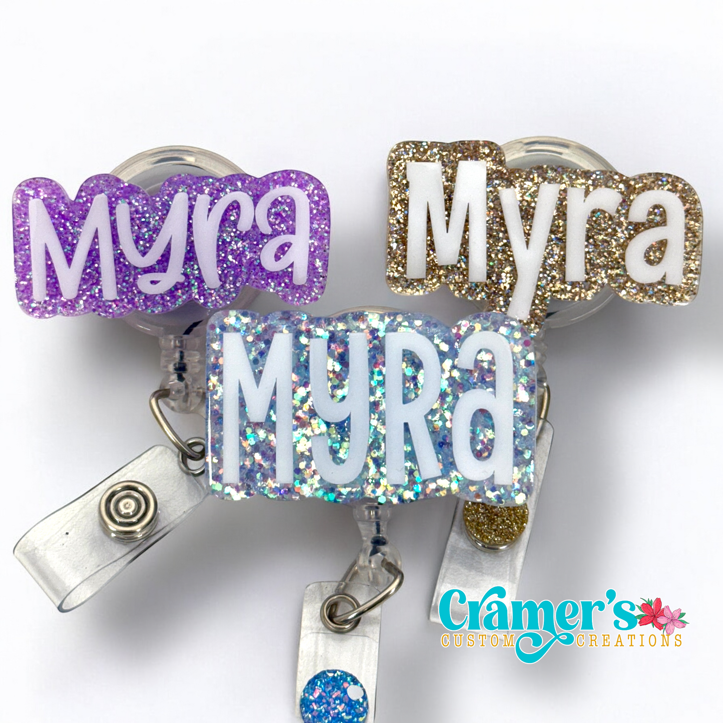 three badge reels with the name myra in 3 different fonts showing the difference in size