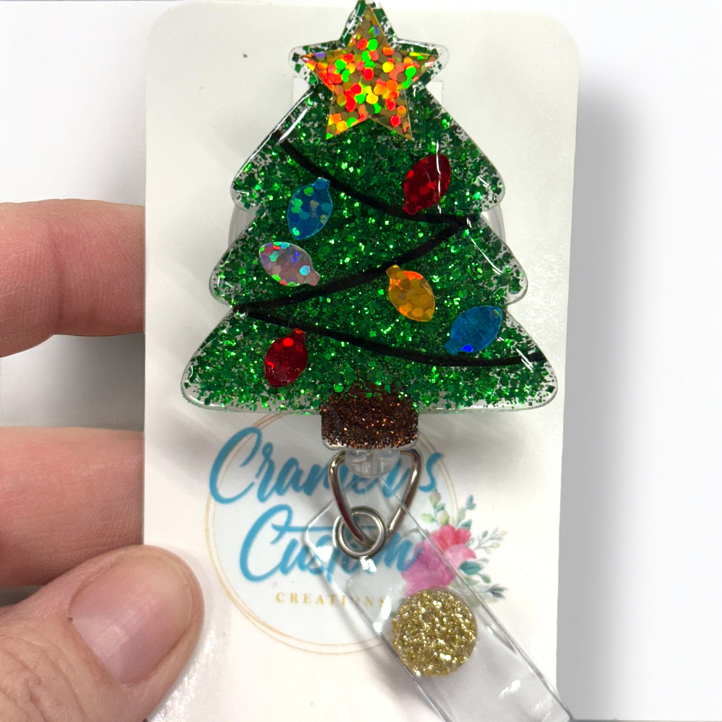 Glittery green christmas tree badge reel with colored bulbs and a gold star
