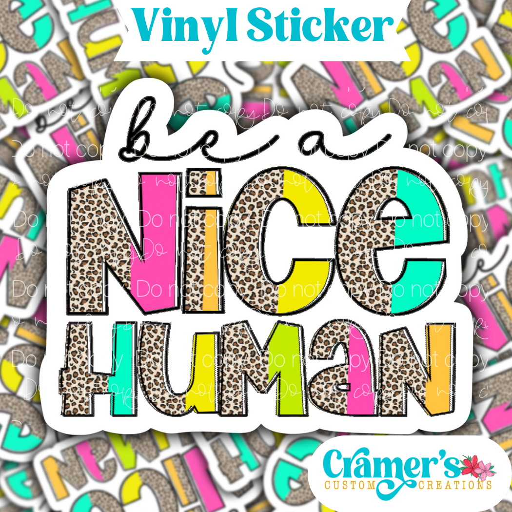 Sticker laying flat that says be a nice human on a background of the same sticker stacked up