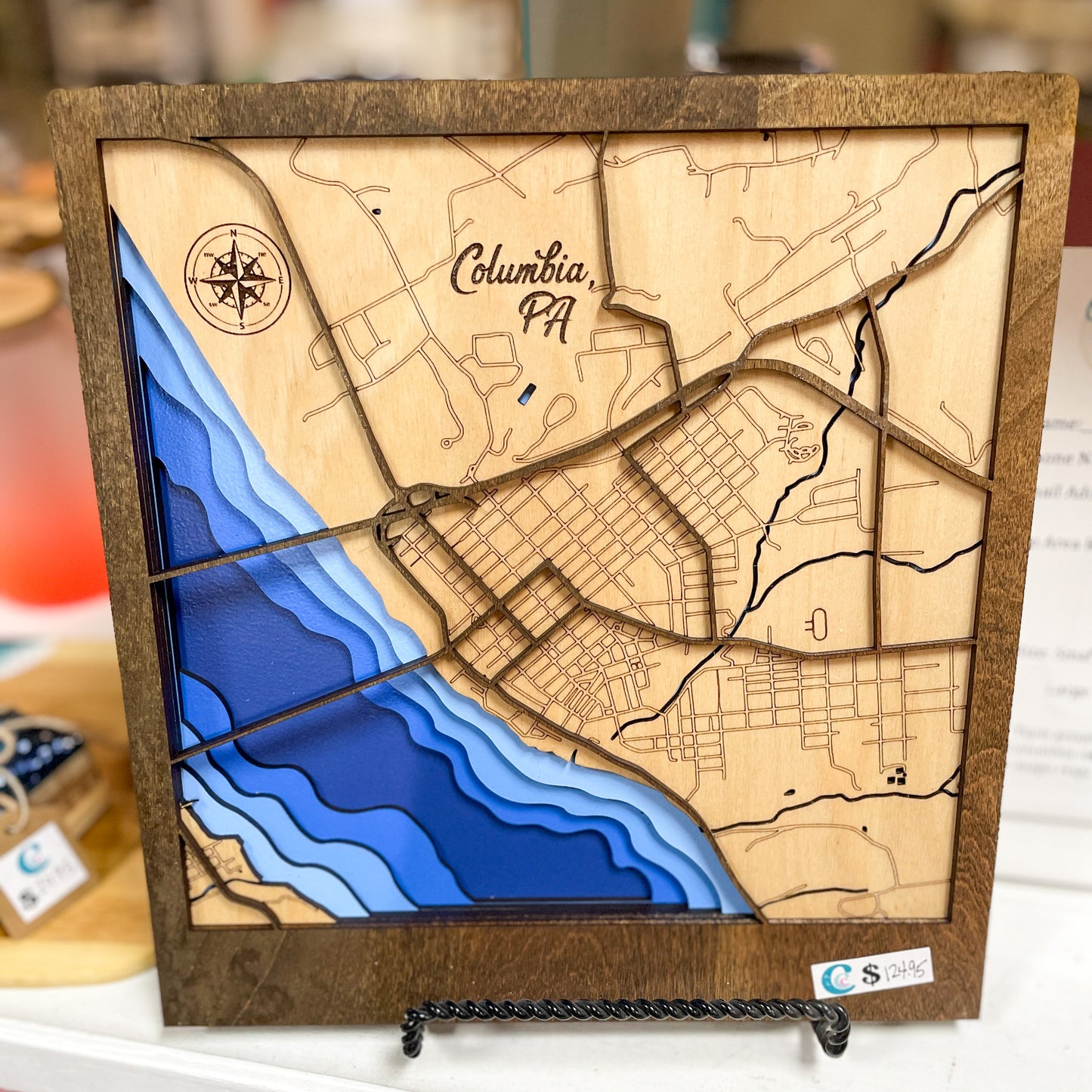 a wood multi layered map painted to show the depth of the river and all the streets shown. Its on a blurred background