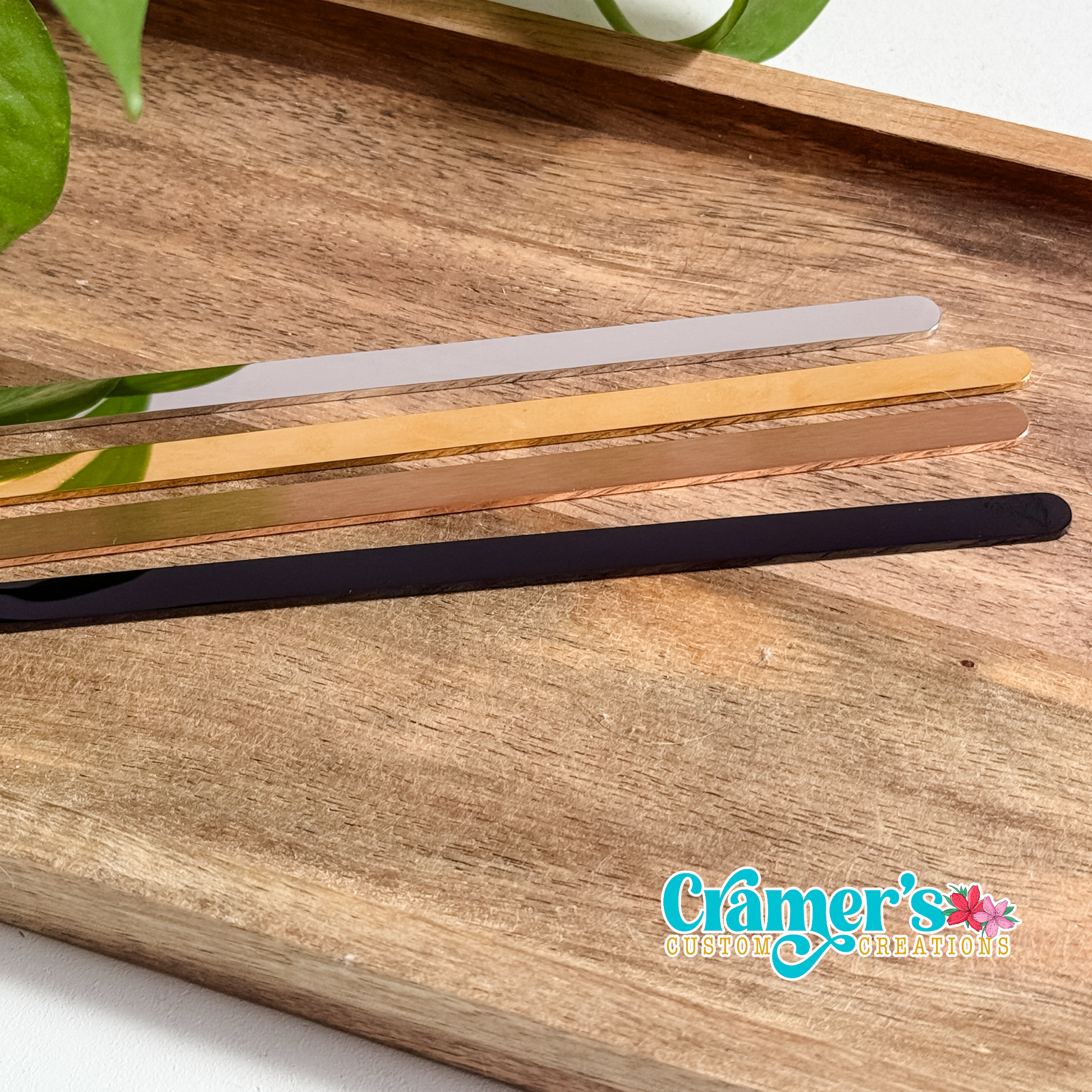 Set of four metal bangle bracelet blanks on a wooden surface with 'Cramer's Custom Creations' logo.