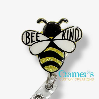 Bee-shaped badge holder with 'BEE KIND' text on a white background, featuring Cramer's Custom Creations logo.