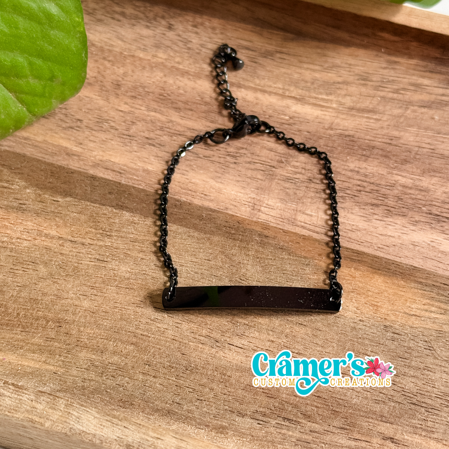 Black bracelet on a wooden surface with 'Cramer's Custom Creations' branding.