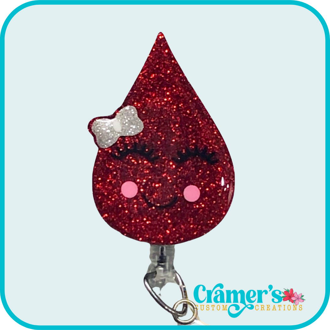 glittery badge reel shaped like a drop of blood with a bow