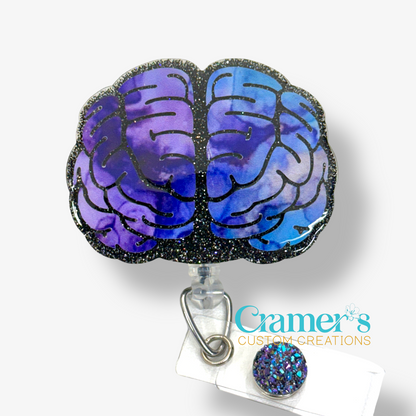 badge reel of a brain with black glitter background and a purple/blue inky vinyl 