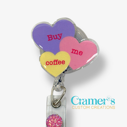 Heart-shaped badge holder with 'Buy me coffee' text on a white background, featuring the brand 'Cramer's Custom Creations'.
