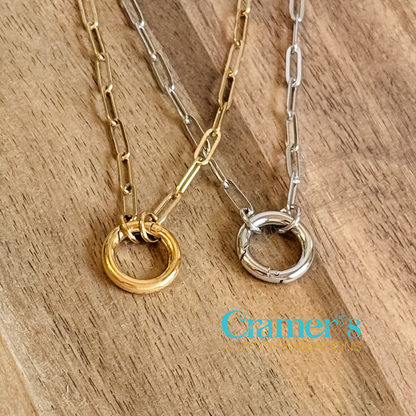 Two necklaces with circular pendants on a wooden surface, featuring Cramer's Custom Creations logo.