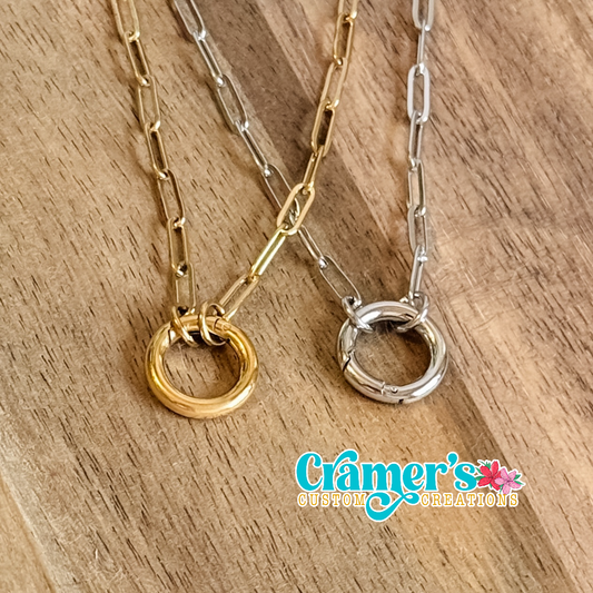 Two necklaces with circular pendants on a wooden surface, featuring Cramer's Custom Creations logo.