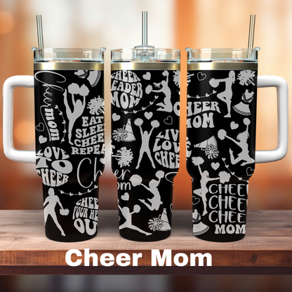 Three 40 oz black tumblers with white text and graphics related to cheerleading, each with a straw, displayed on a wooden surface with the text 'CHEER MOM' at the bottom.