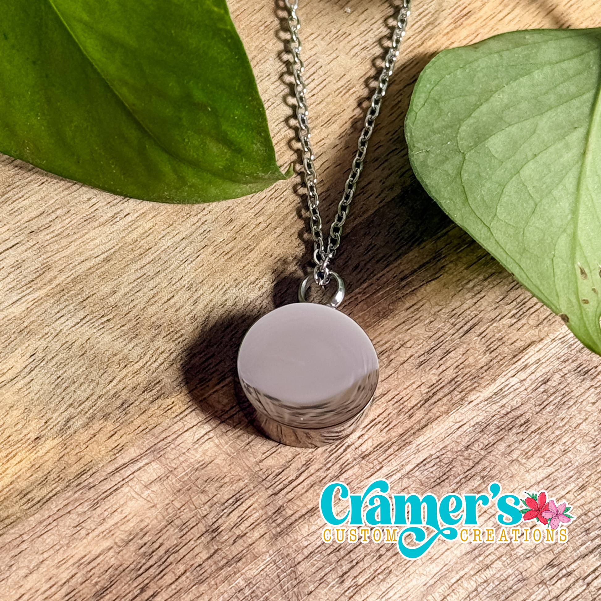 a silver circle urn necklace on a wood background