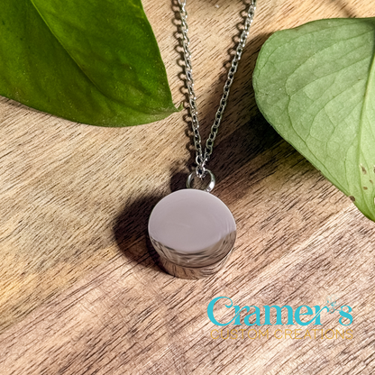 a silver circle urn necklace on a wood background