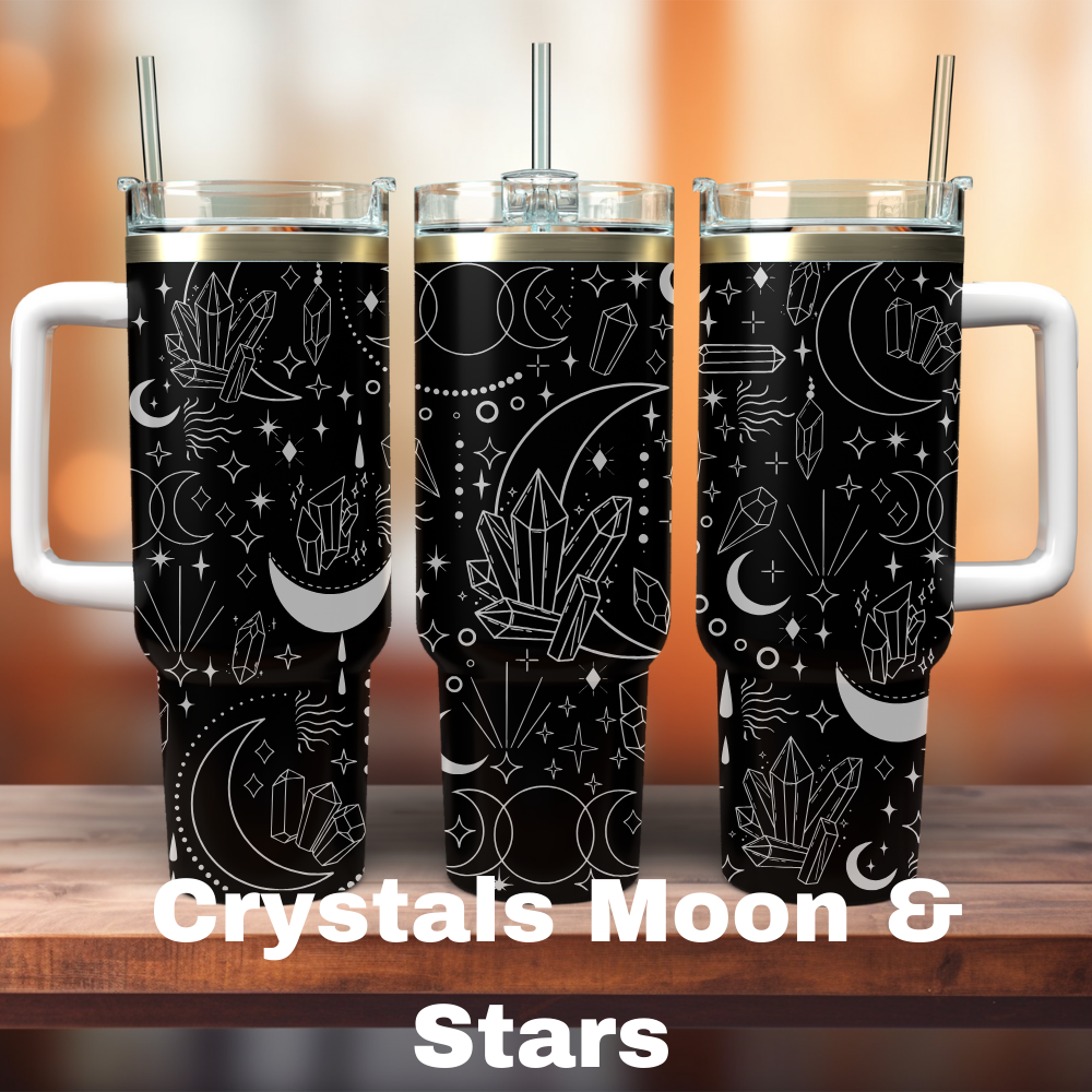 Three 40 oz tumblers with a black background, featuring laser engraved designs of crystals, moons, and stars. One tumbler has a straw, and the design is spread across the surface of both tumblers.