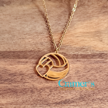 Gold necklace with a volleyball pendant on a wooden surface, featuring the 'Cramer's Custom Creations' logo.