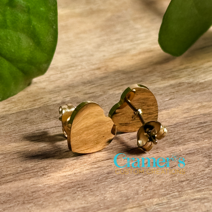 a pair of gold heart stud earrings on a wood background