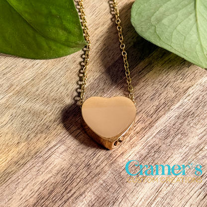a gold heart urn necklace on a wood background