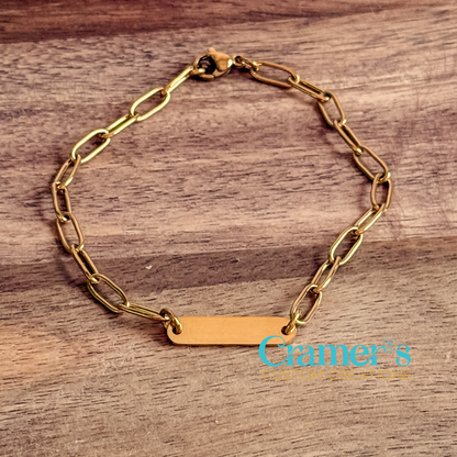 Gold chain bracelet on a wooden surface with 'Cramer's Custom Creations' branding.