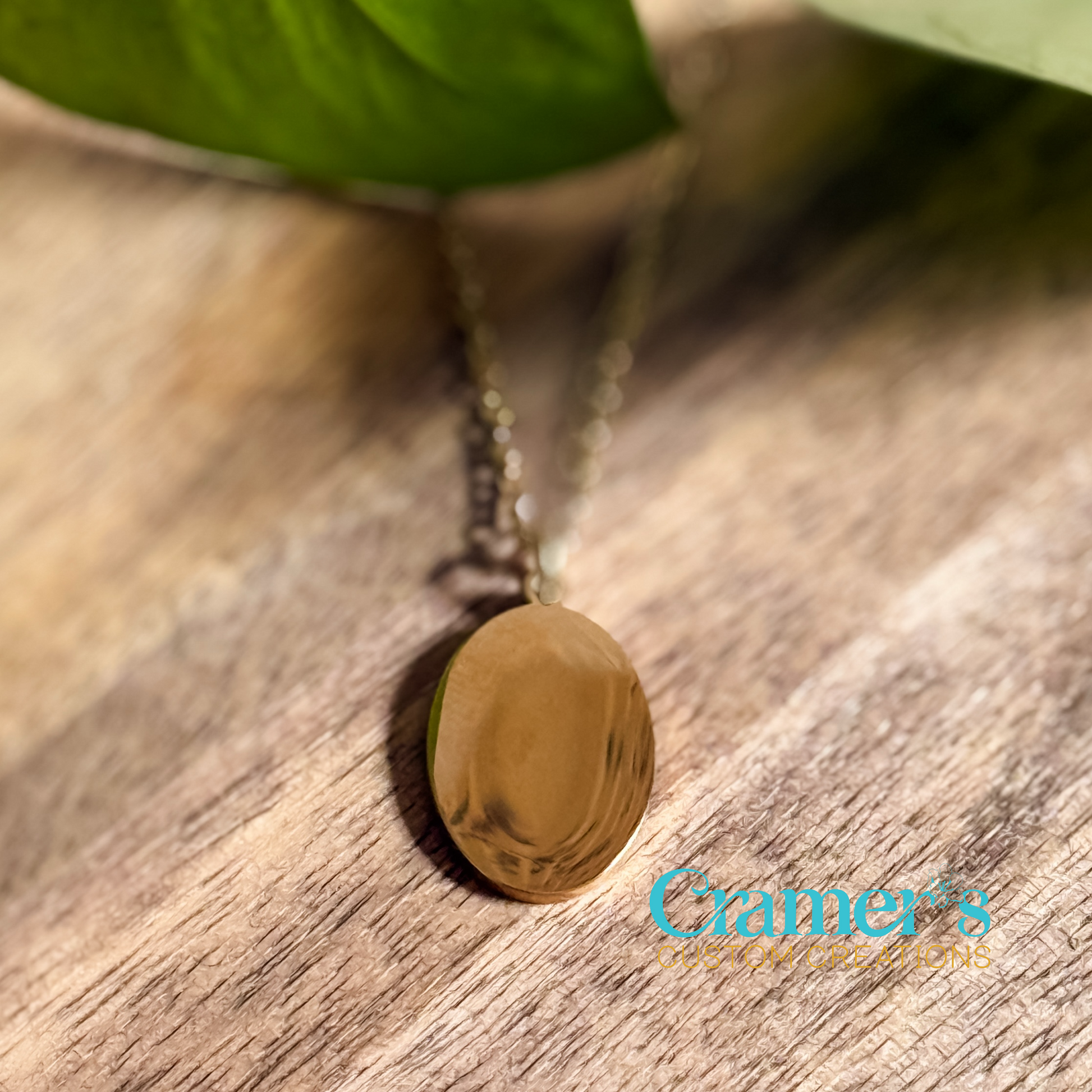a gold oval pendant necklace on a wood background