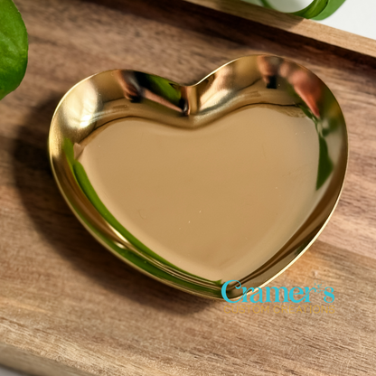 Gold heart-shaped dish on a wooden surface with 'Cramer's Custom Creations' branding.