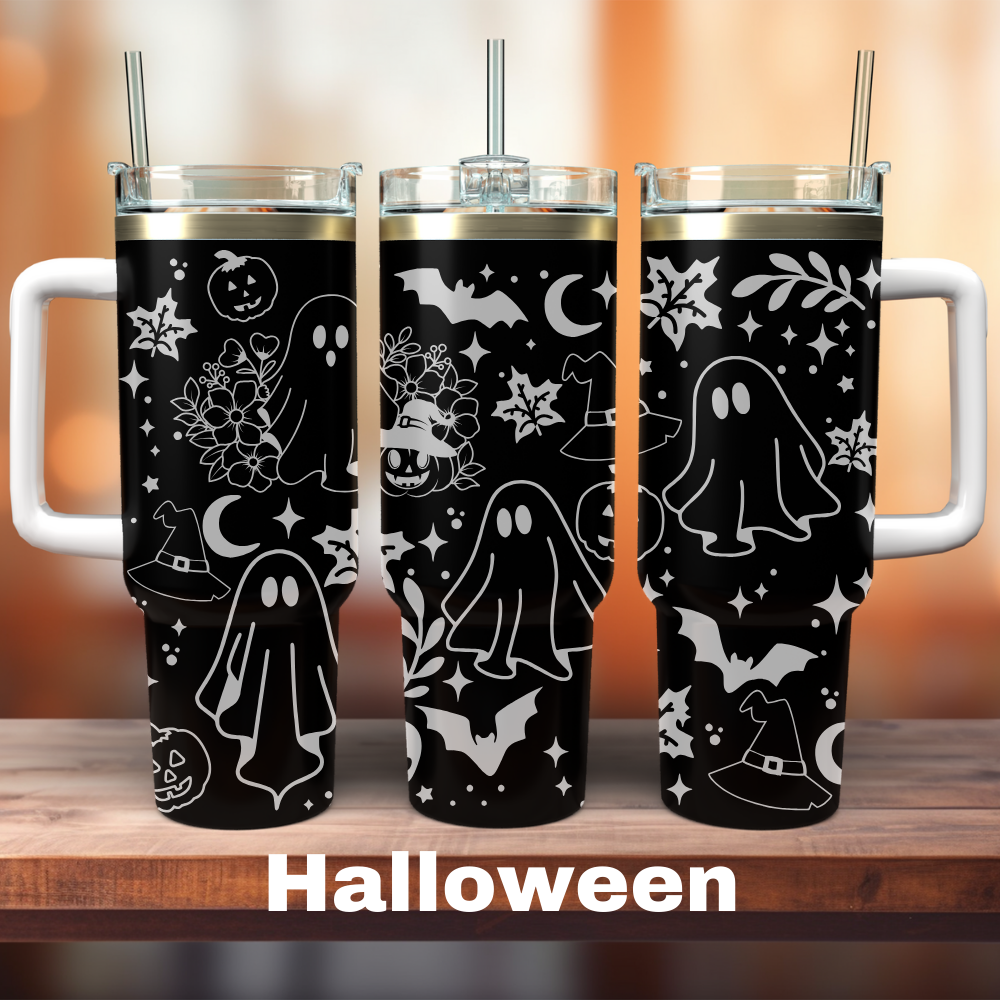 Three 40 oz black tumblers with laser engraved Halloween designs, including ghosts, bats, and pumpkins, displayed on a wooden surface with a blurred background.
