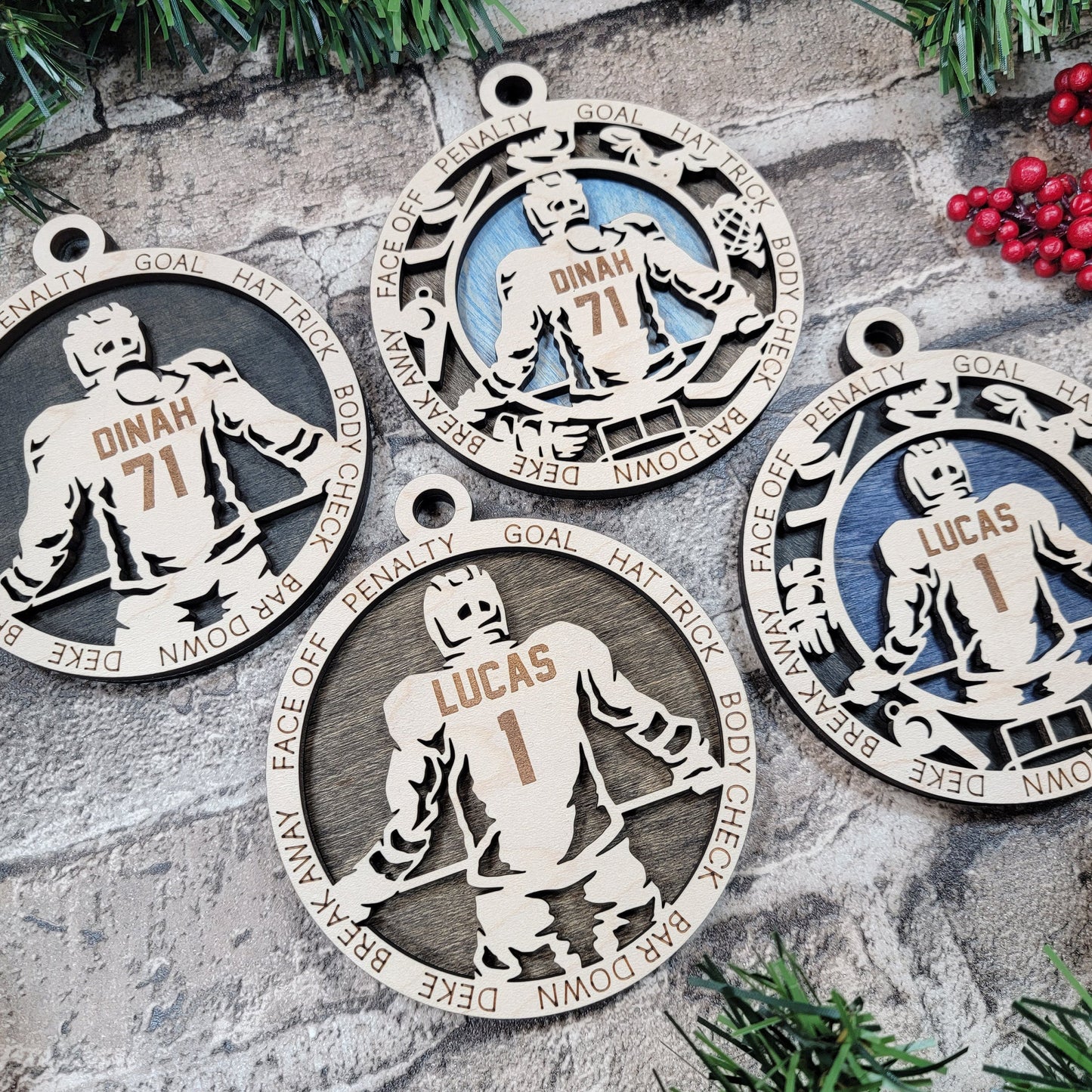 Set of hockey-themed Christmas ornaments on a stone surface with greenery and berries.