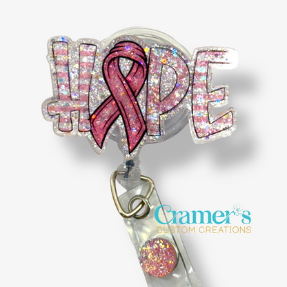 A badge reel showing the word hope with a ribbon as the letter O with a pink color and glitter back ground