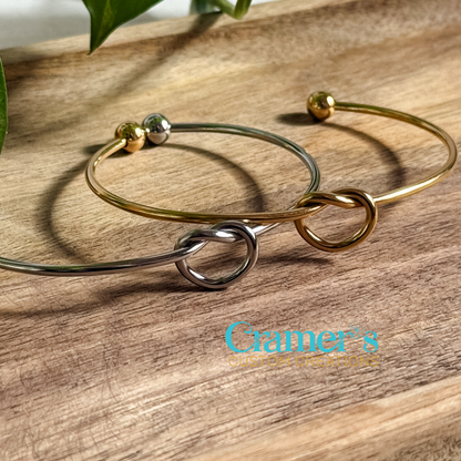 Silver and gold bracelets laying on a wood background