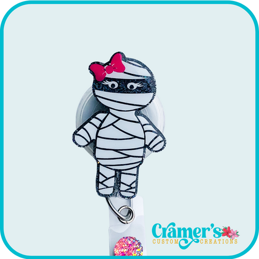 a badge reel shaped like a mummy with a pink bow