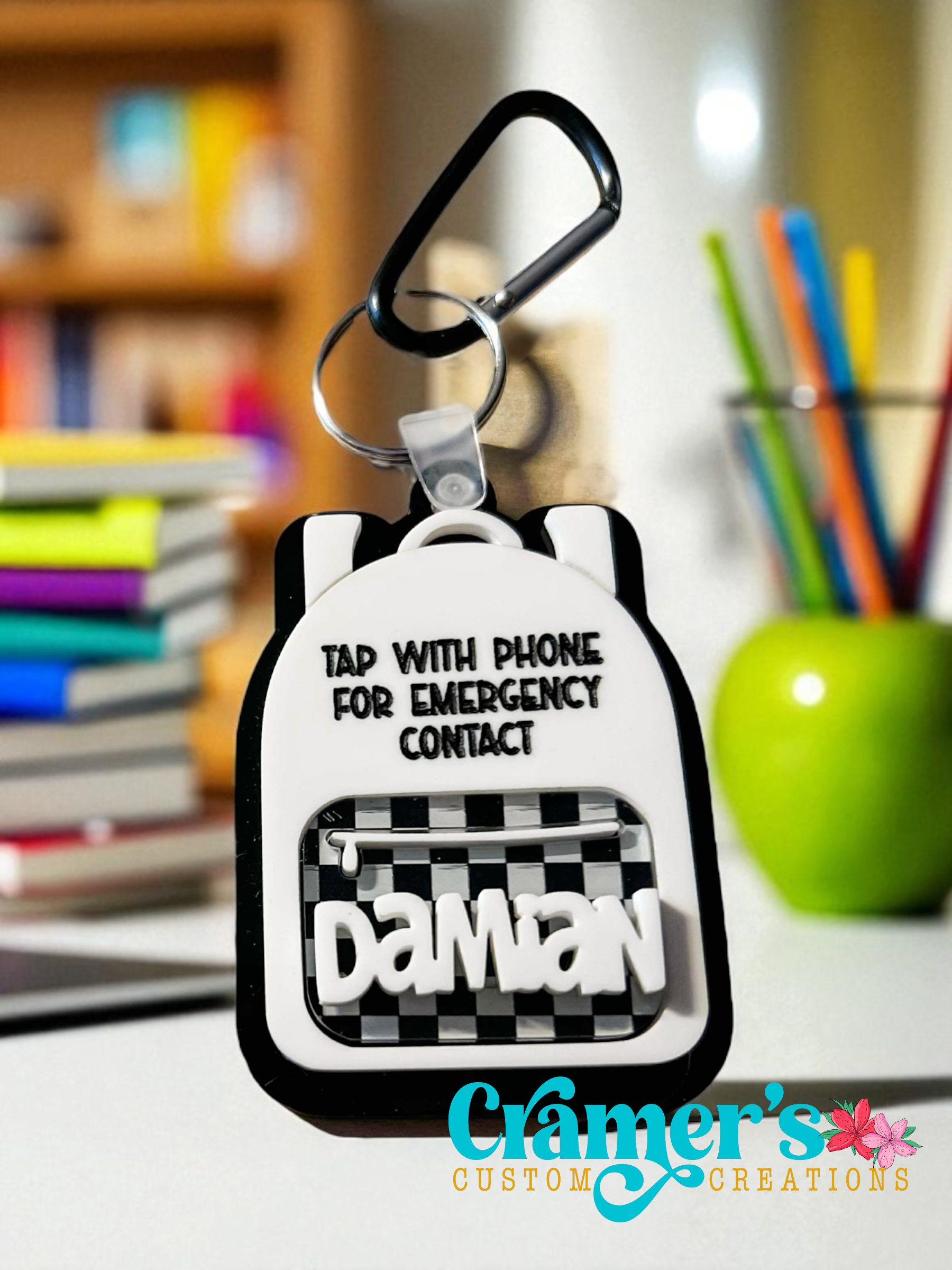 Keychain with emergency contact feature on a desk with books and pens in the background
