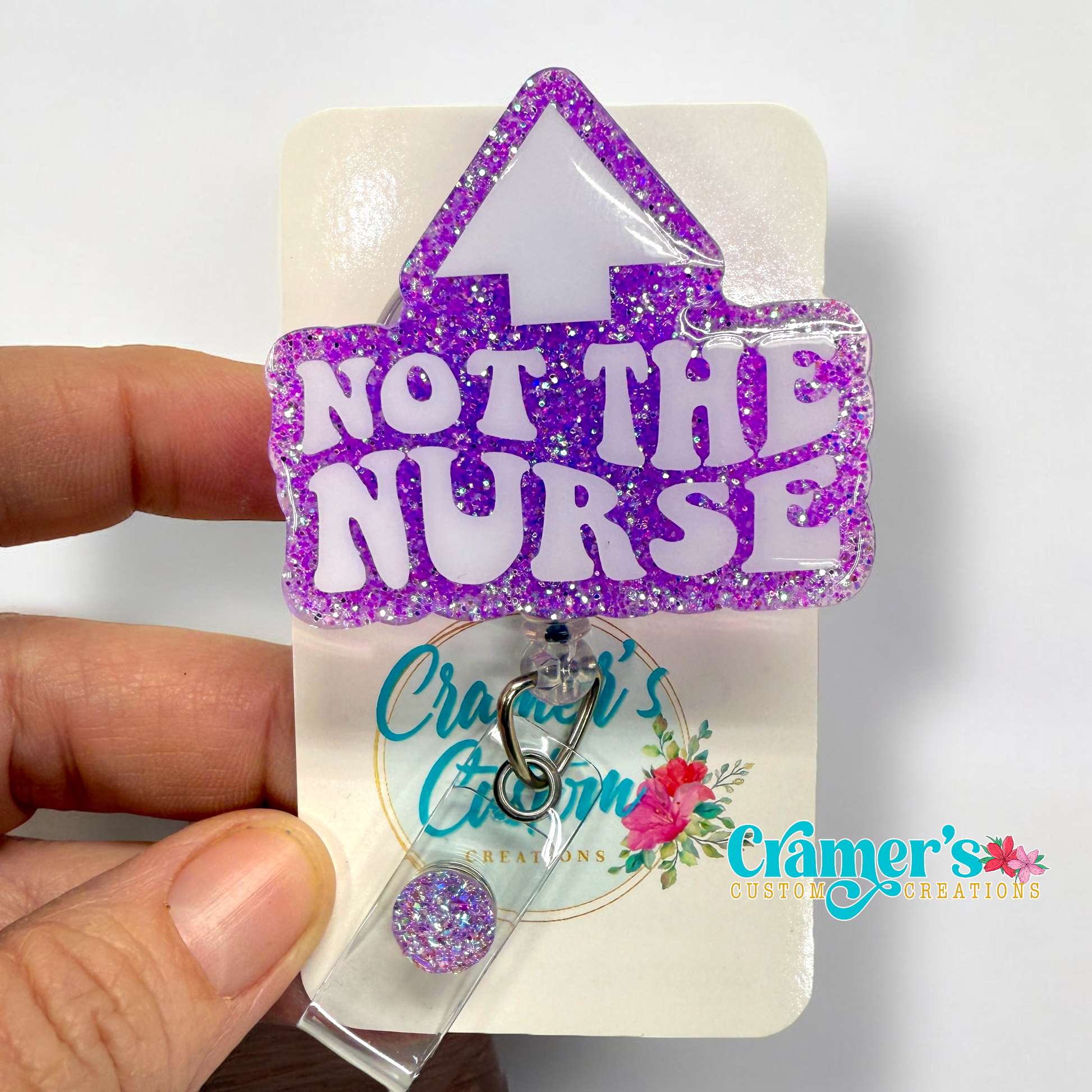 badge reel showing a purple glitter background with not the nurse in white with an arrow pointing up