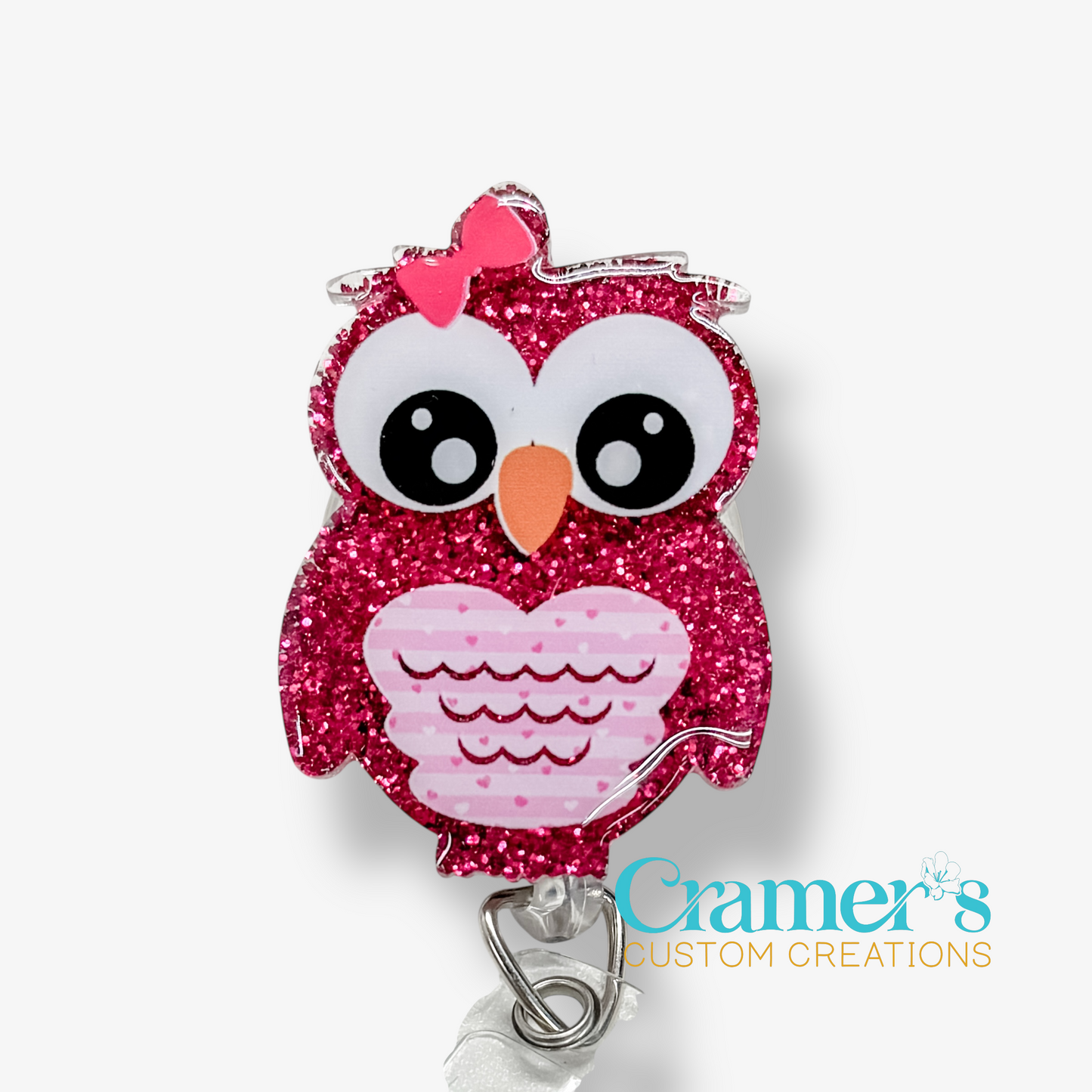 Pink glittery owl-shaped badge holder with a pink bow on a white background, featuring the brand 'Cramer's Custom Creations'.