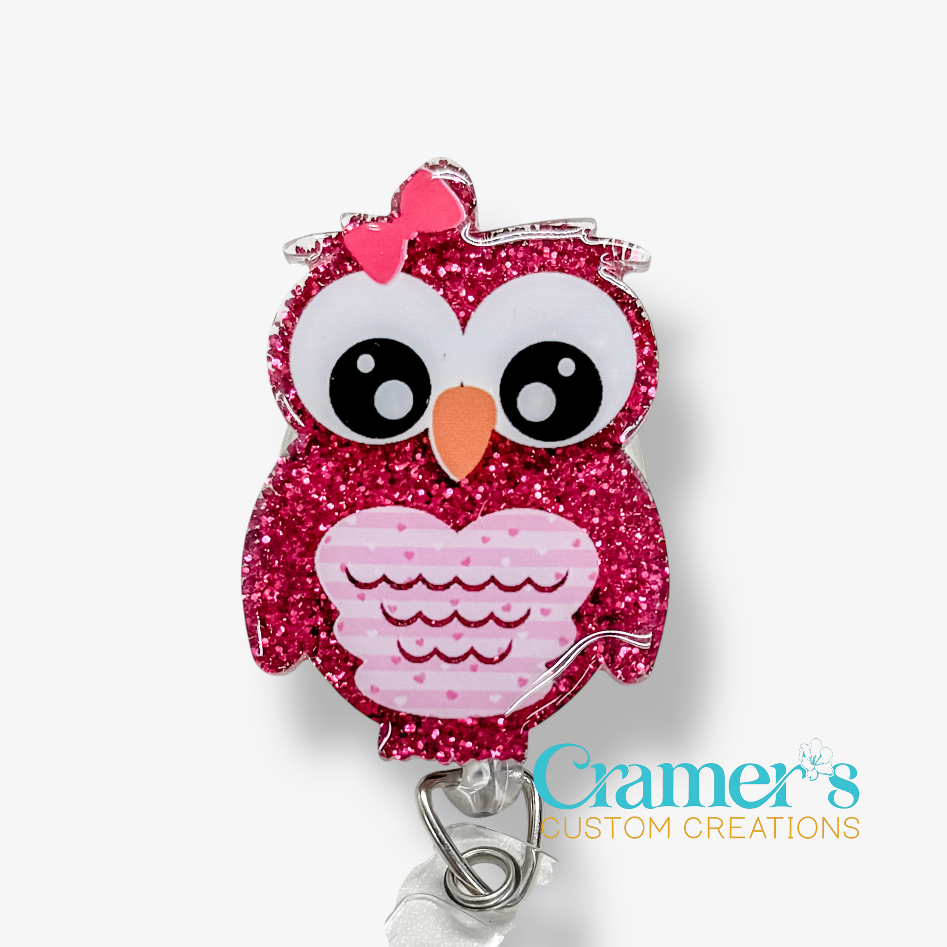 Pink glittery owl-shaped badge holder with a pink bow on a white background, featuring the brand 'Cramer's Custom Creations'.
