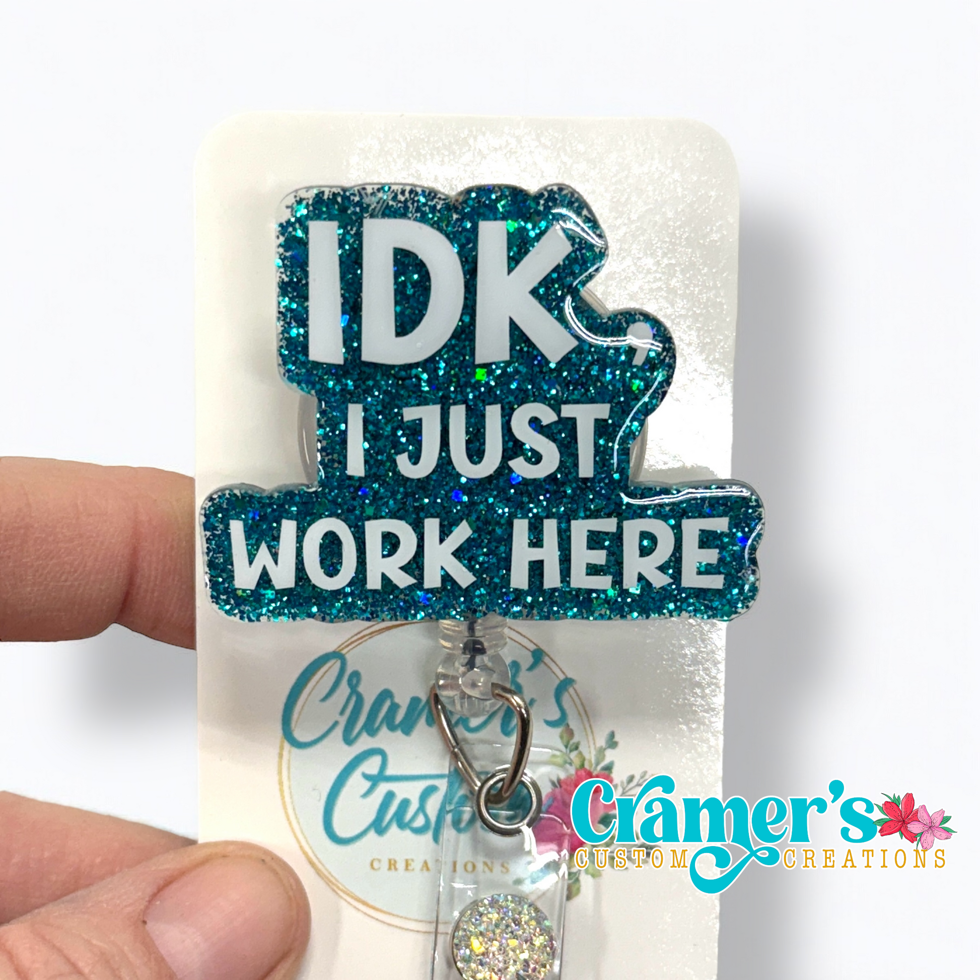 badge reel showing a teal glitter background with idk, i just work here in white