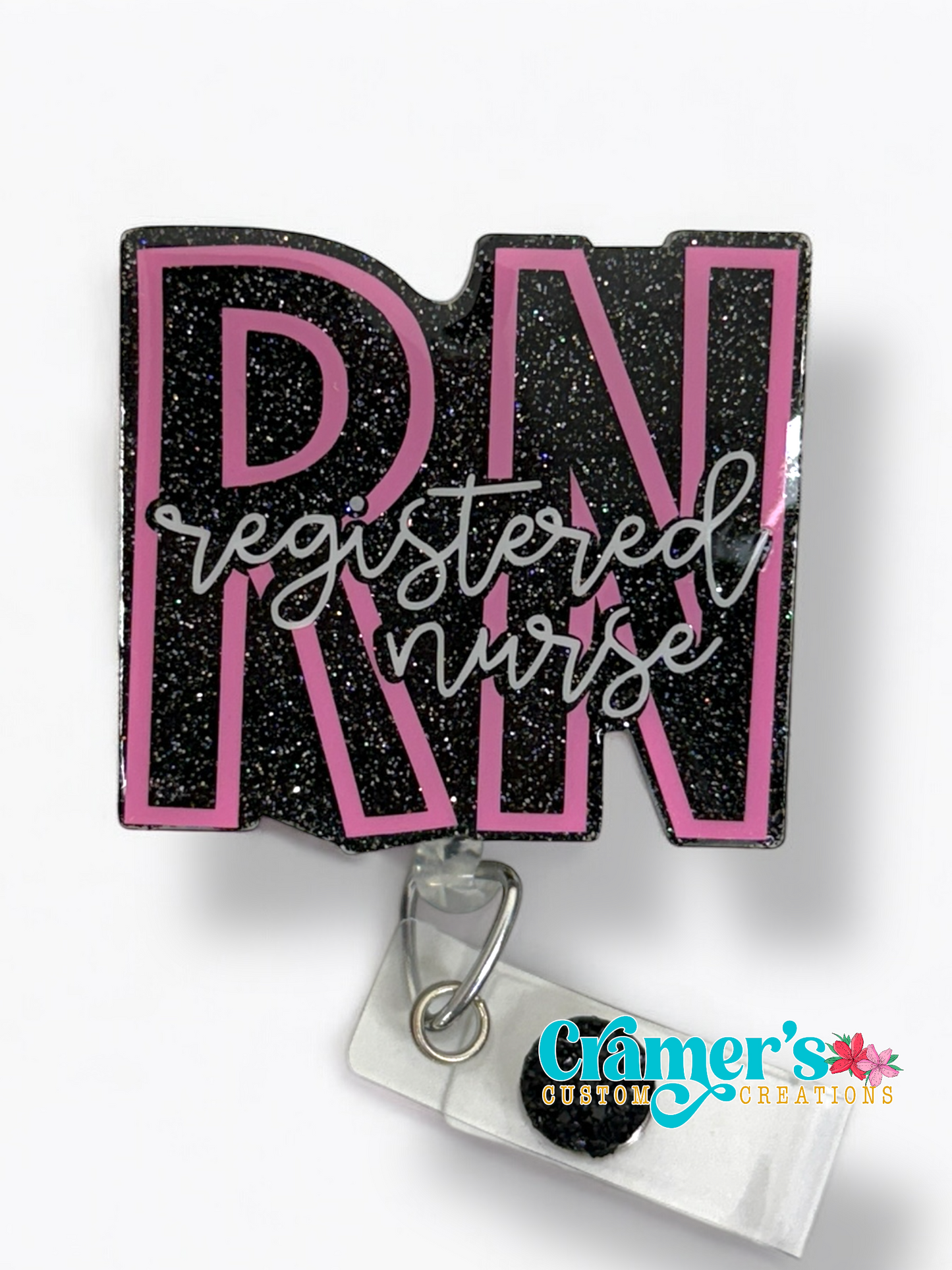 badge reel showing a black glitter background with the initials in pink and registered nurse in white 