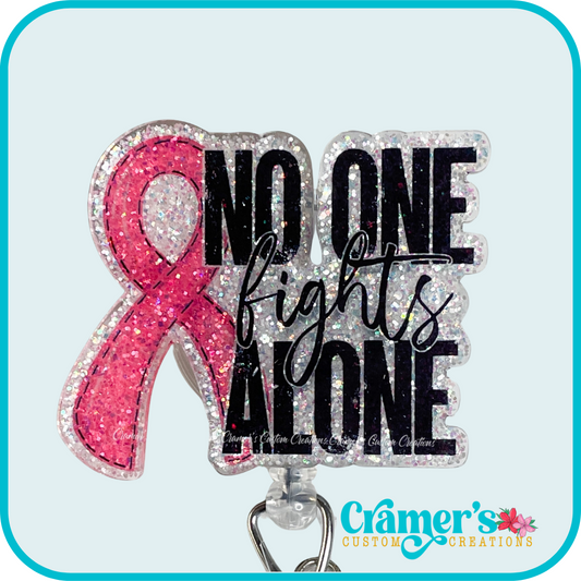 a glittery badge reel saying no one fights alone with a pink ribbon