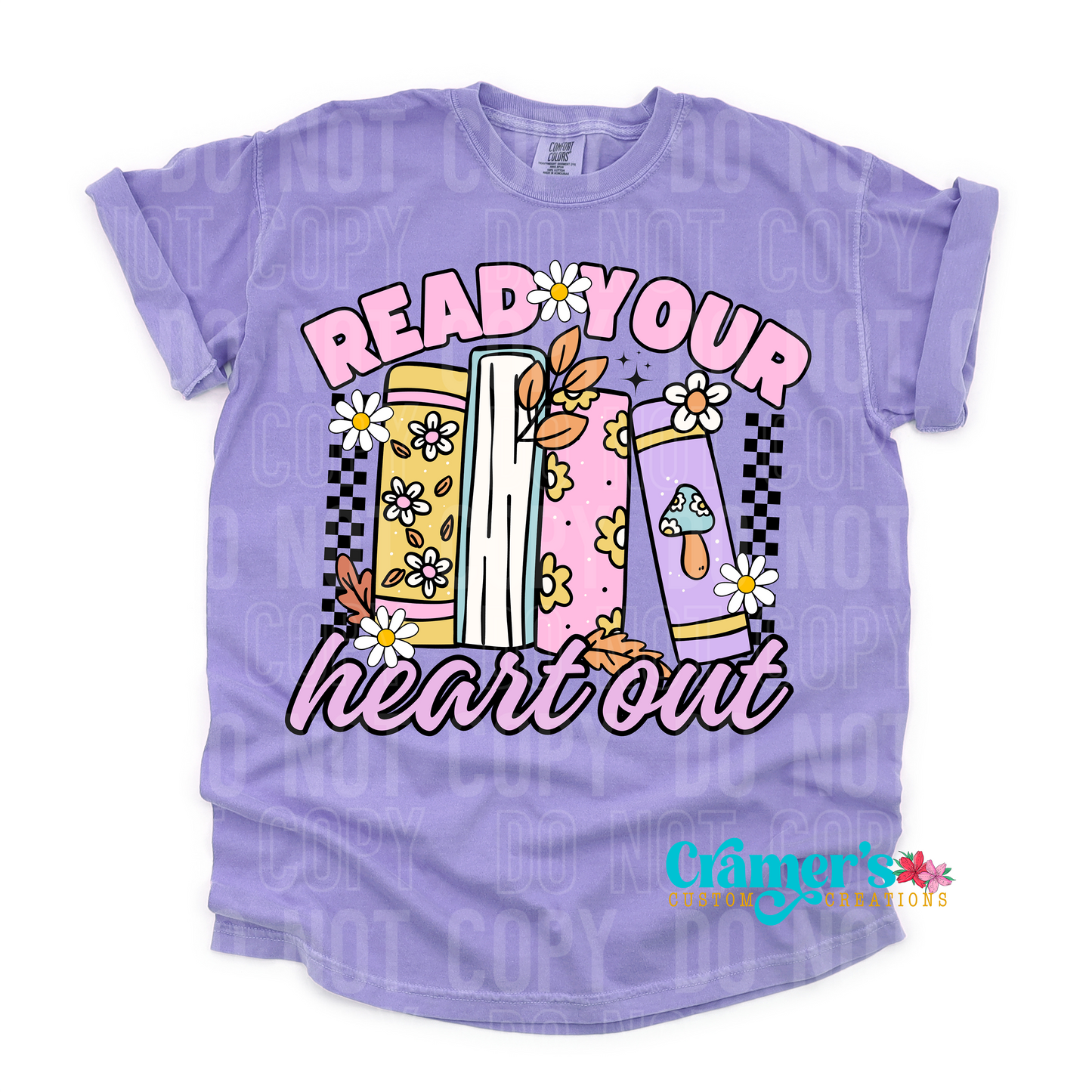 purple flat lay of a shirt that says read your heart out, in pink writing and some books on a bookshelf