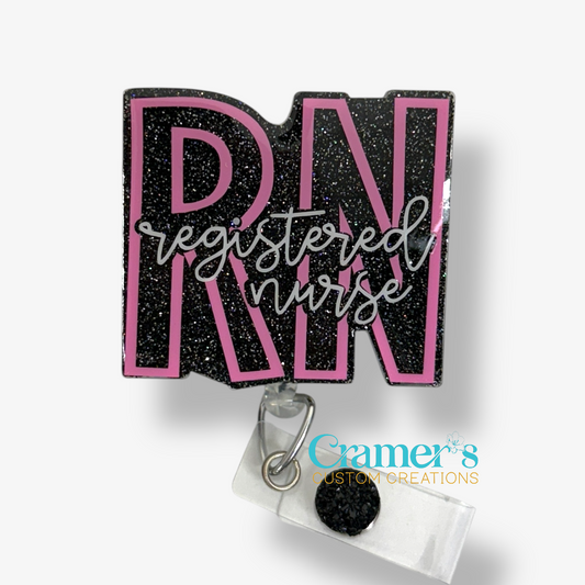badge reel showing a black glitter background with the initials in pink and registered nurse in white 