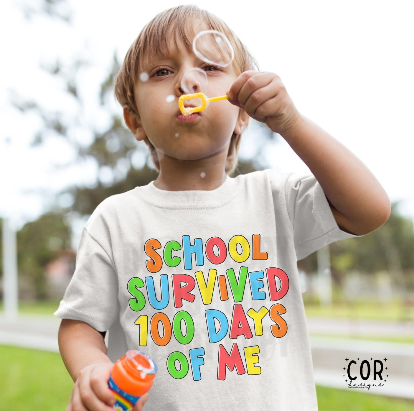 Little boy blowing bubbles with a shirt that says school survived 100 days of me