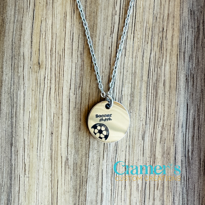 15mm circle necklace with a soccer ball engraved on a wood background