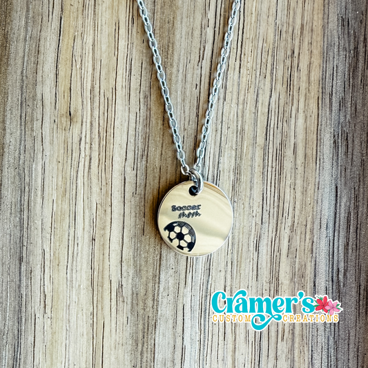 15mm circle necklace with a soccer ball engraved on a wood background