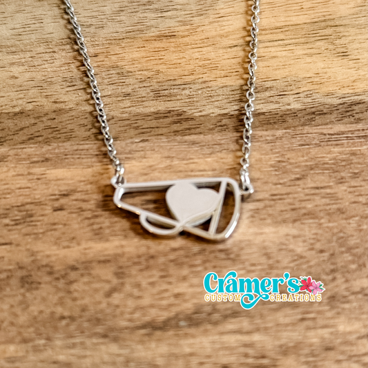 Silver necklace with a cheer megaphone pendant on a wooden surface, featuring Cramer's Custom Creations logo.