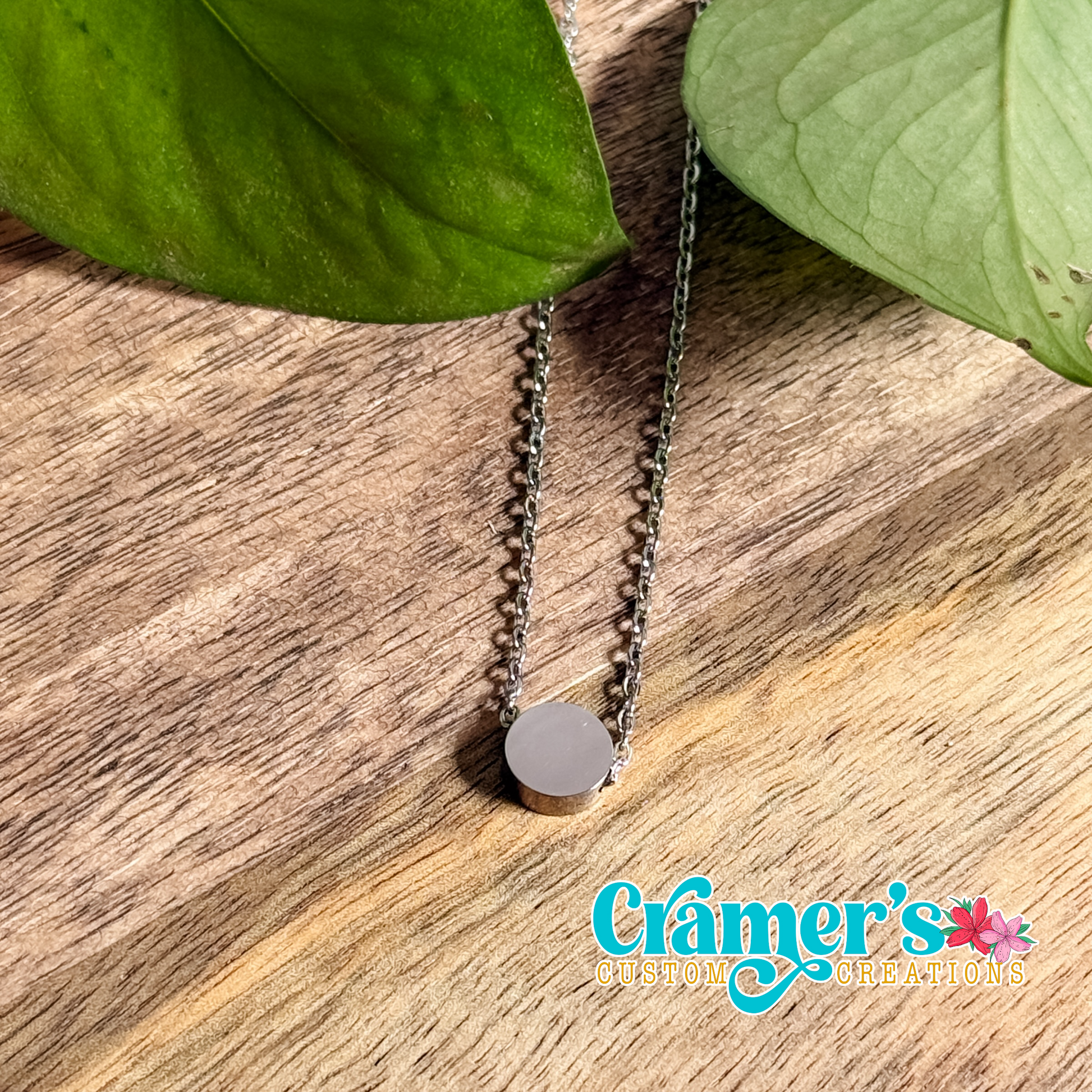 a small silver circle pendant necklace on a wood background