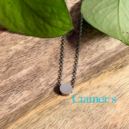 a small silver circle pendant necklace on a wood background