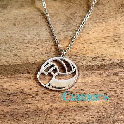 Silver necklace with a volleyball pendant on a wooden surface, featuring Cramer's Custom Creations logo.