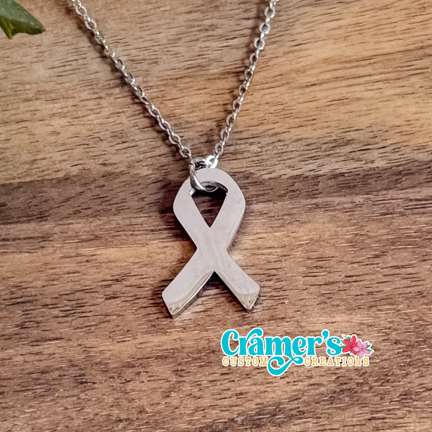 Silver ribbon pendant necklace on a wooden surface with 'Grifer's Custom Creations' branding.