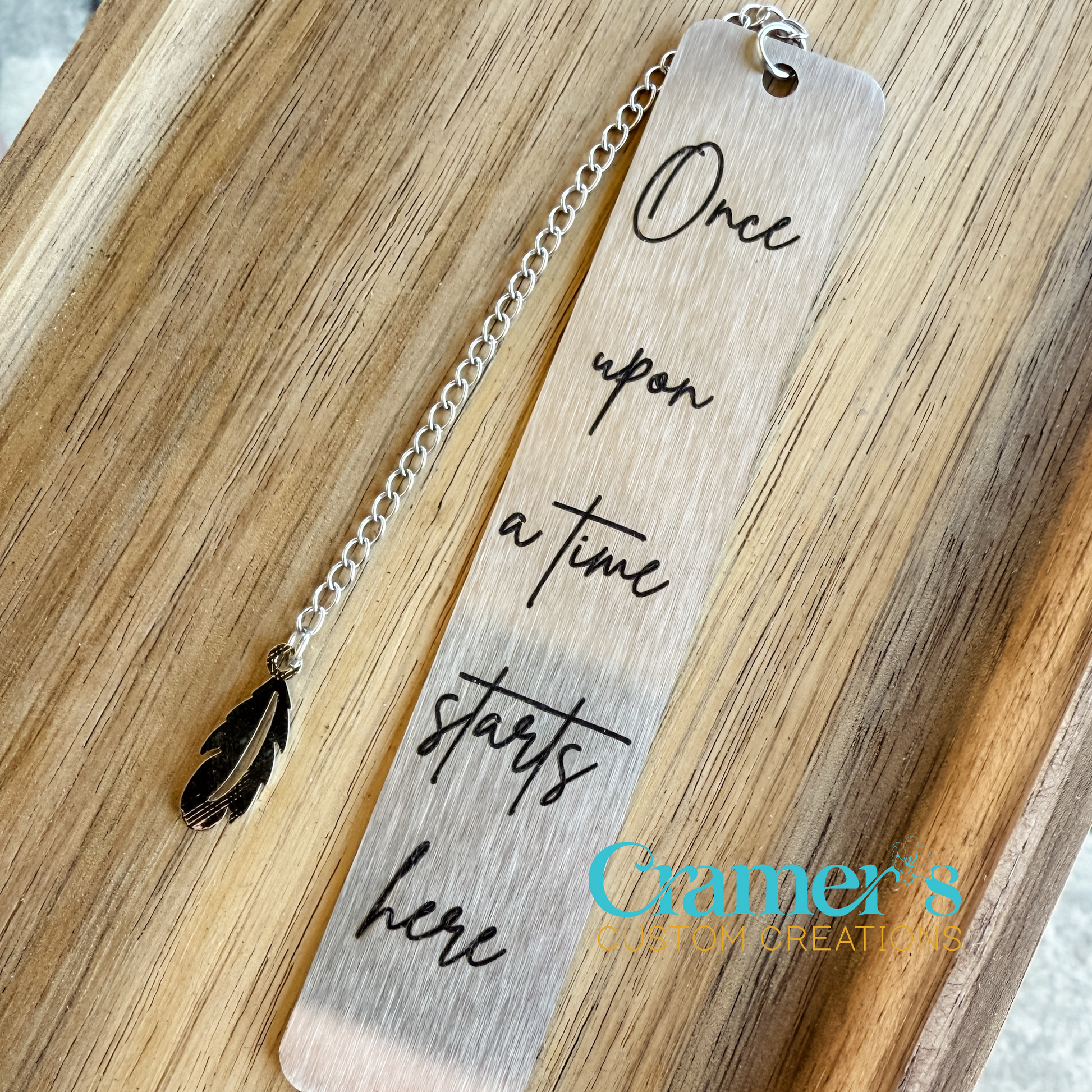 Silver bookmark with a phrase on it, laying on a wood background