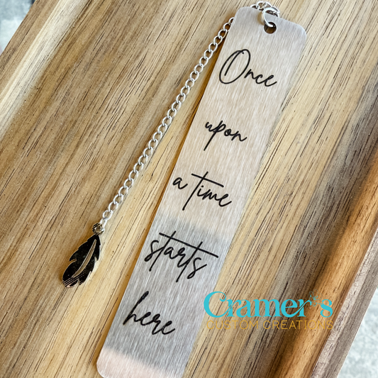 Silver bookmark with a phrase on it, laying on a wood background