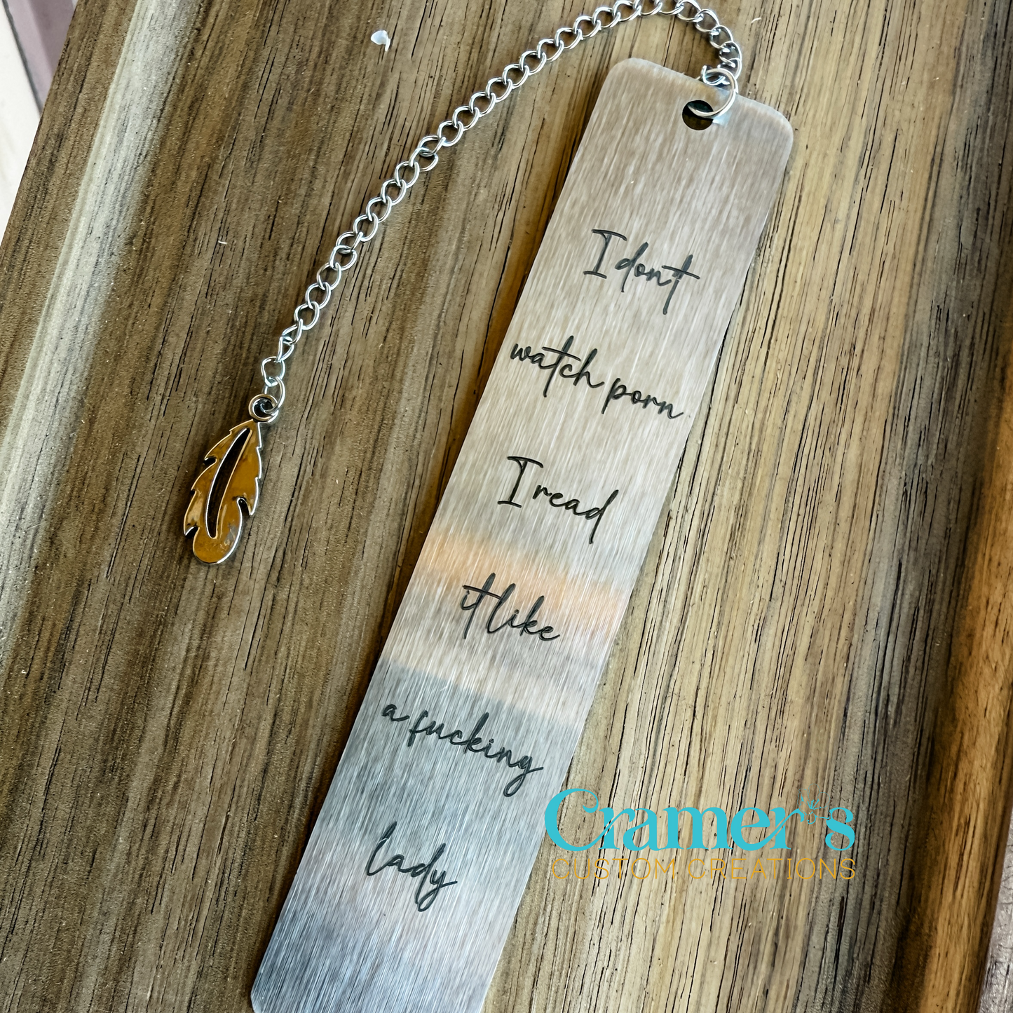 Silver book mark engraved with phrase, lying on a wood background