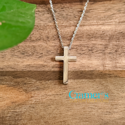 Silver cross necklace on a wooden surface with 'Cramer's Custom Creations' branding.