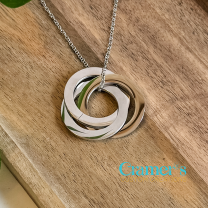 Necklace with interlocking rings on a wooden surface, featuring Cramer's Custom Creations logo.